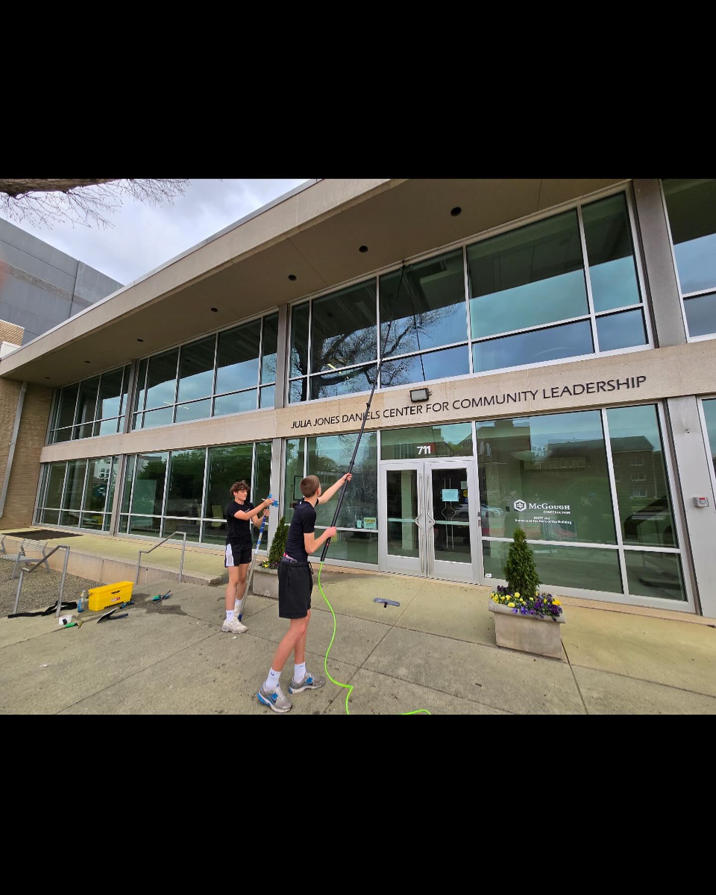 Team washing a commercial building with water-fed poles