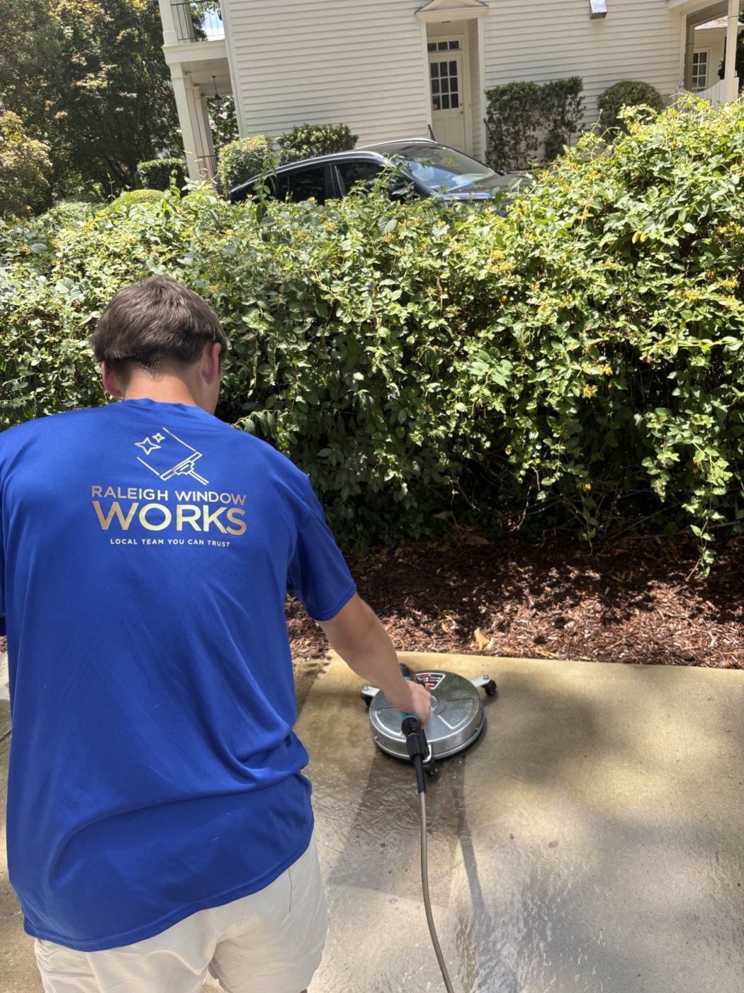 Power washing a driveway in the Raleigh Window Works shirt