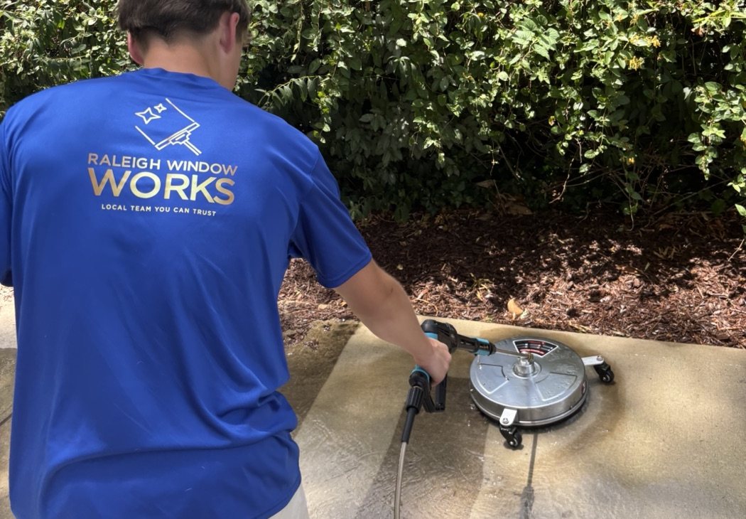 Raleigh Window Works team member power washing a driveway with a surface cleaner
