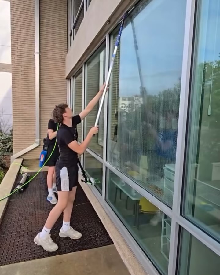 Students washing windows with a water-fed pole